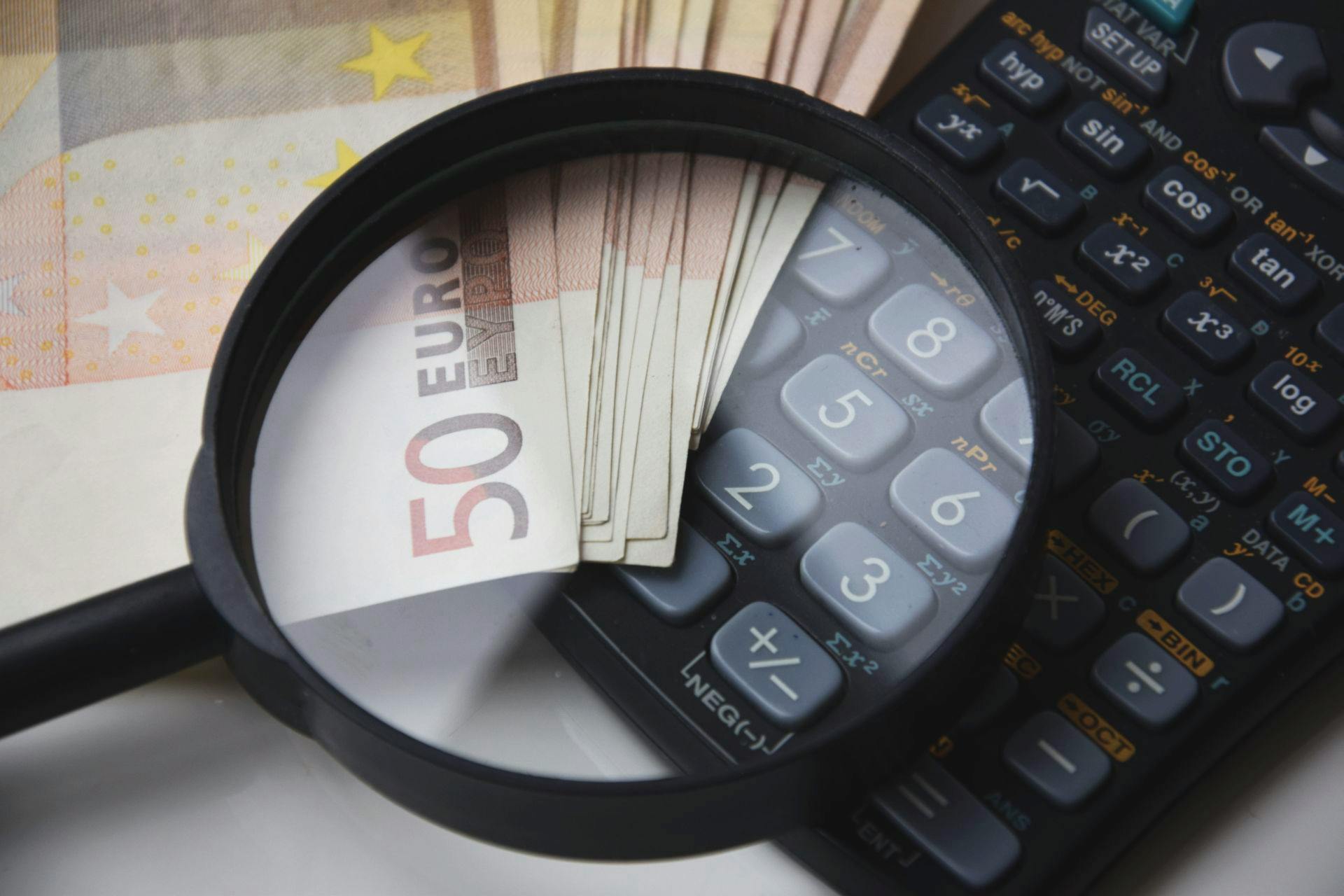 Calculadora y billetes con una lupa encima
